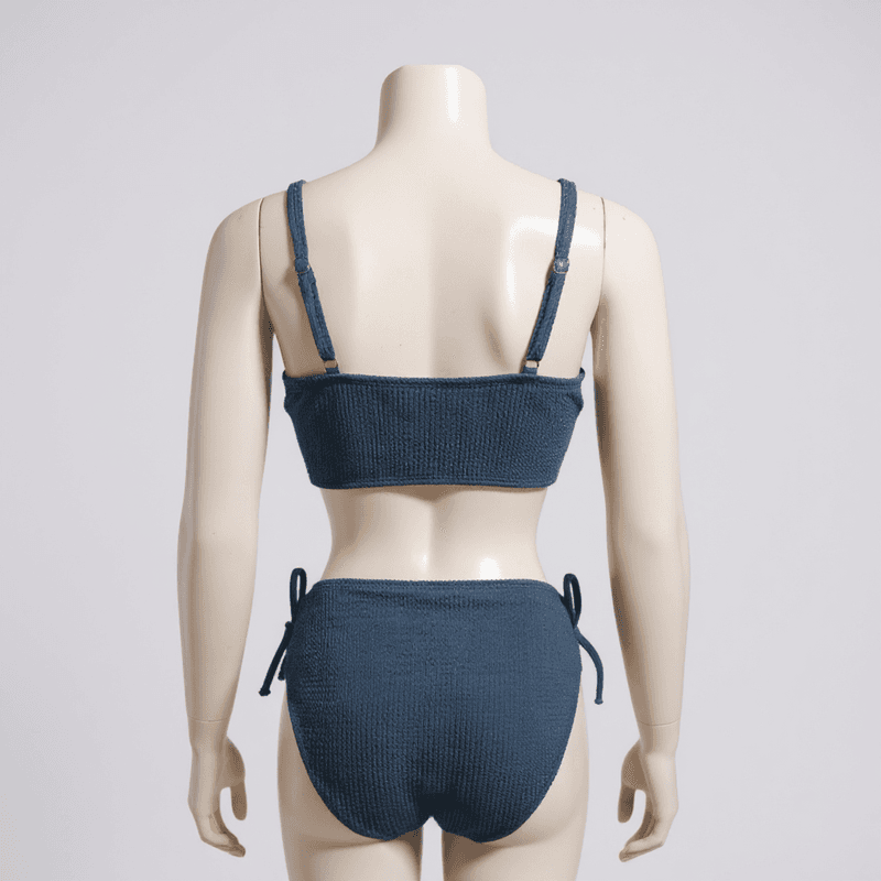 Elegante conjunto de bikini en tono azul marino, con un top bandeau y braguita clásica, ideal par...